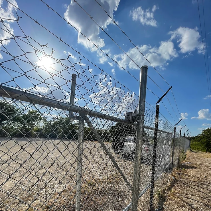 Chain link fence with barbed wire on top, built at a municipal construction site.