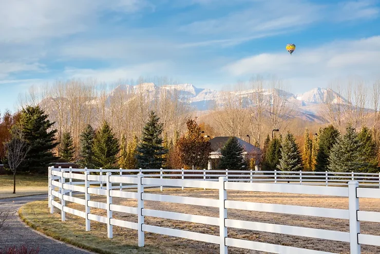Mountainous skyline with white agricultural fencing blocking off a pasture.