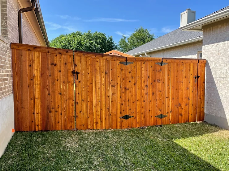 Dark-stained wooden fence connecting two back yards in a neighborhood in Austin.