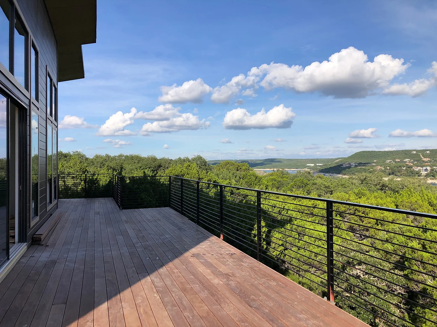 Custom wooden deck with a black iron fence surrounding it, looking over Lake Travis.