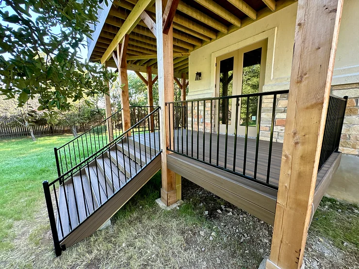 Wooden elevated deck with stairs leading down into an Austin, Texas back yard.