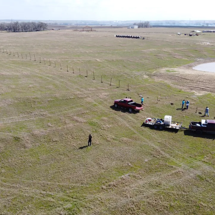 Aerial view of a Sagamore Fence & Deck crew and trucks on a ranch fence project in an open pasture