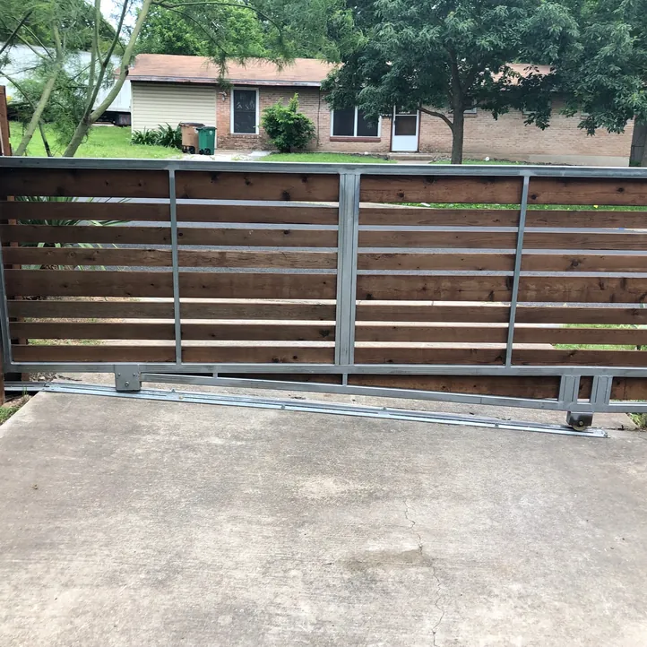 Automatic horizontal cedar and steel cantilever slide gate across a concrete driveway