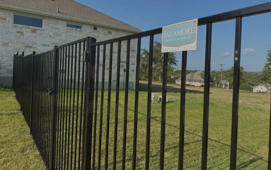 Black iron fence along the side yard of a stone home, built by Sagamore Fence & Deck for Belton, TX homes