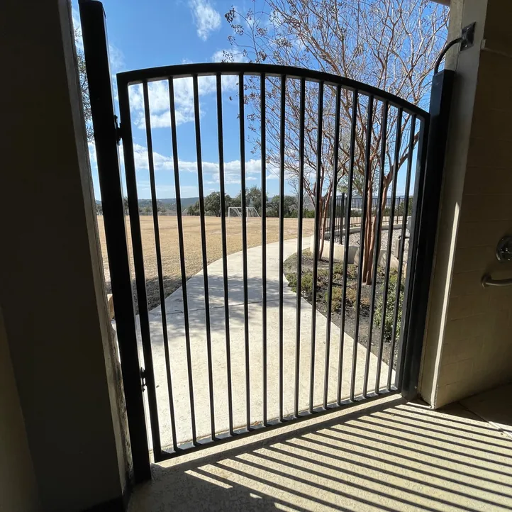 Black arched iron walk gate opening from a covered patio