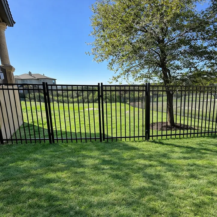 Black flat-top ornamental iron fence running from a stone-column covered patio across a green backyard
