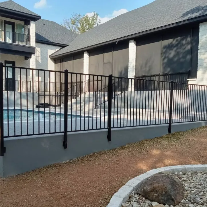 Black iron pool fence on a raised concrete pool deck