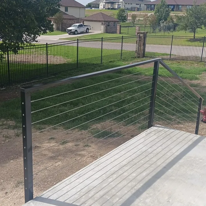 Black metal cable railing along the edge of a concrete patio