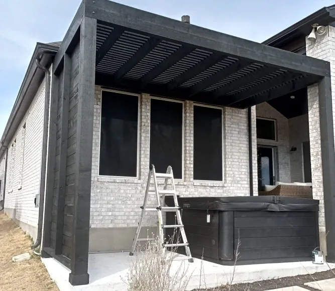 Black-stained wood pergola over a back patio and hot tub, built by Sagamore Fence & Deck in Central Texas