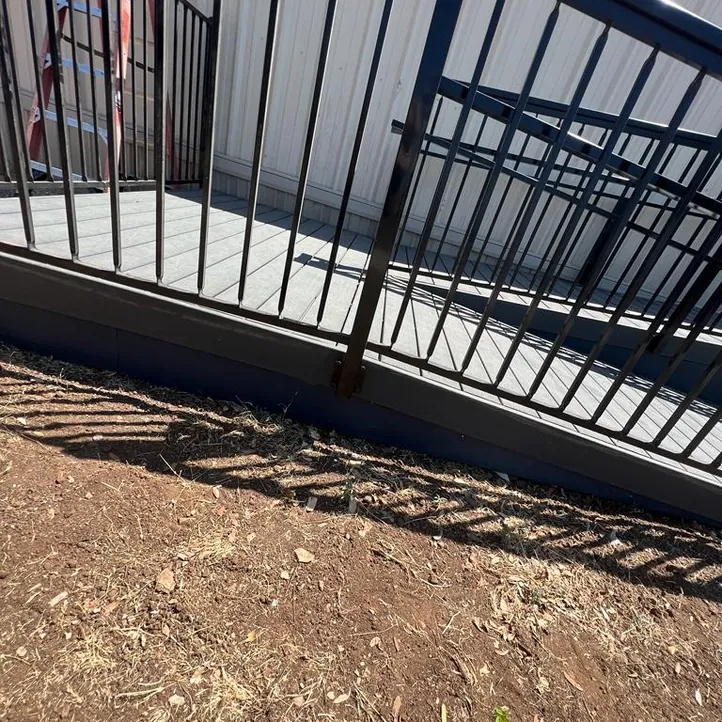 Black steel railing along concrete steps and a walkway