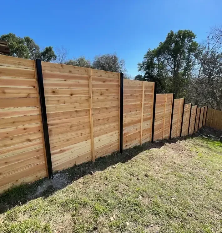 Horizontal cedar fence with black steel posts on a sloped backyard, built by Sagamore Fence & Deck for Burnet, TX homes