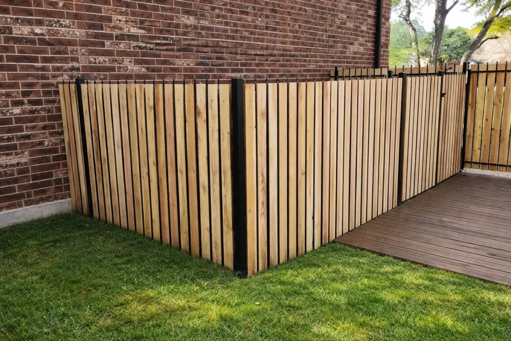 Natural cedar boards in a black steel frame forming a privacy screen beside a brick home and wood deck