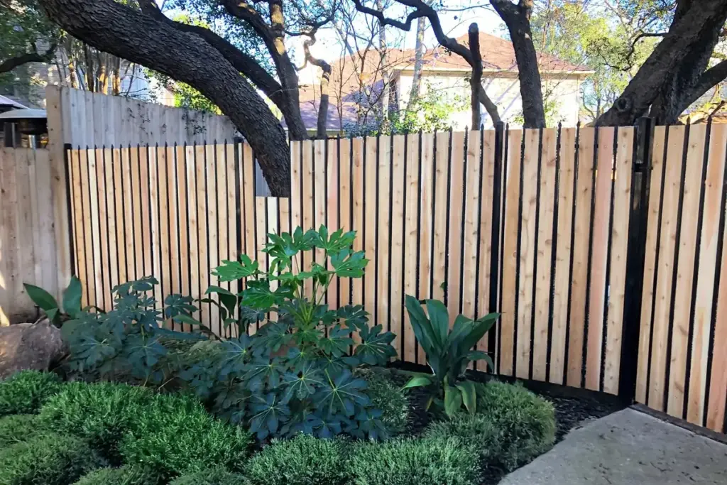 Cedar fence on black steel posts behind a landscaped garden bed