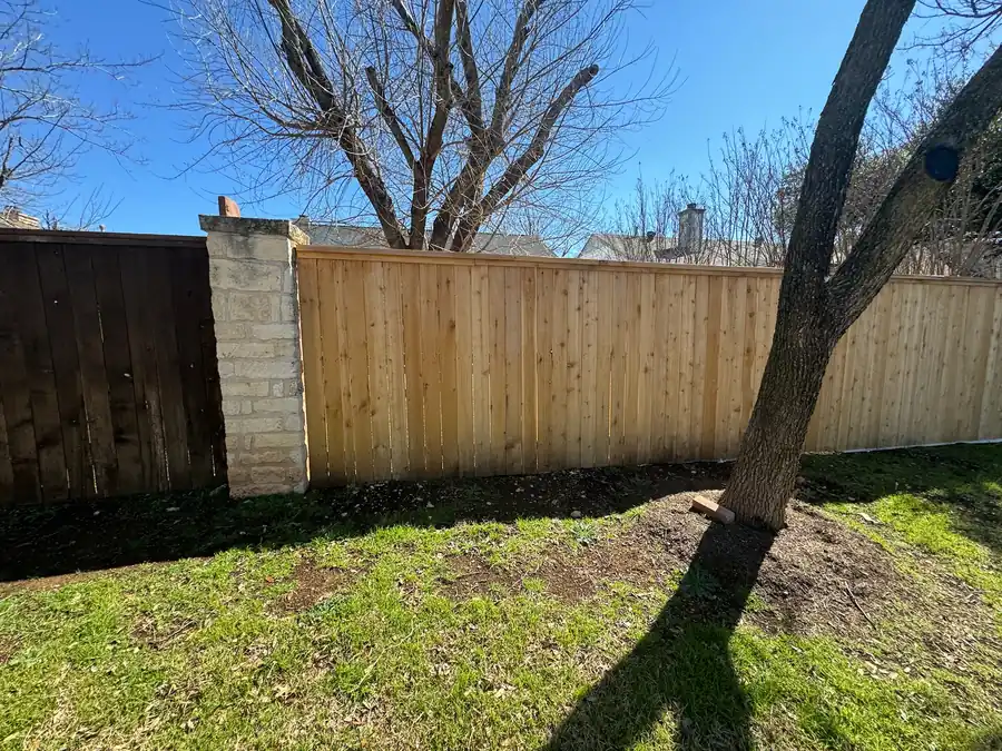 New wood privacy fence next to an older dark-stained section and a stone column, by Sagamore Fence & Deck for Cedar Park, TX homes
