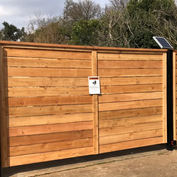 Horizontal cedar double driveway gate on a black steel frame with a solar-powered gate operator
