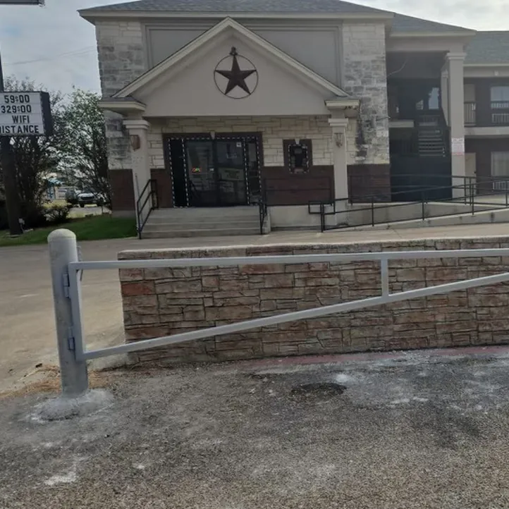Galvanized steel swing-arm gate at the entrance of a commercial parking lot