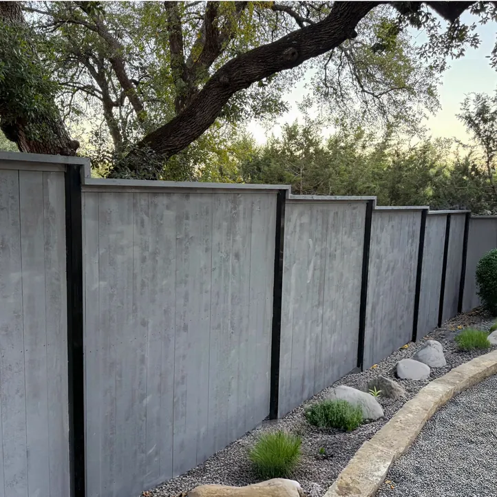 Gray stained wood privacy fence with black posts above a rock garden