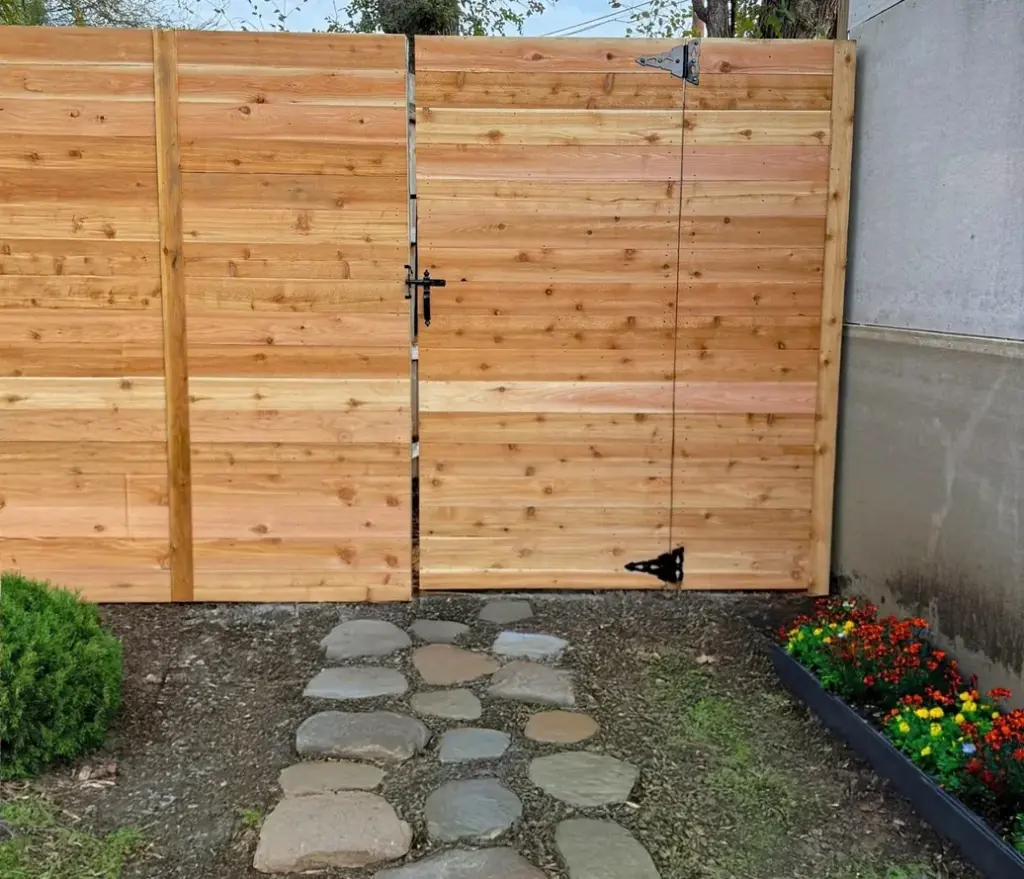Horizontal cedar double gate at the end of a stepping-stone path