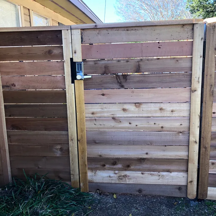 Horizontal cedar walk gate with a keypad lock between cedar fence panels