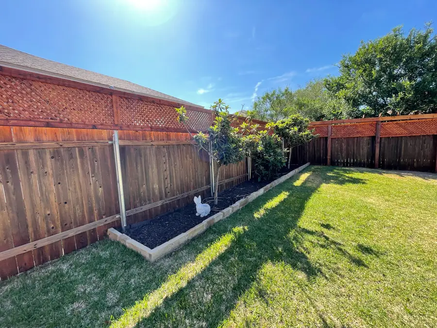 Cedar privacy fence with a raised garden bed along a green backyard, built by Sagamore Fence & Deck for Hutto, TX homes