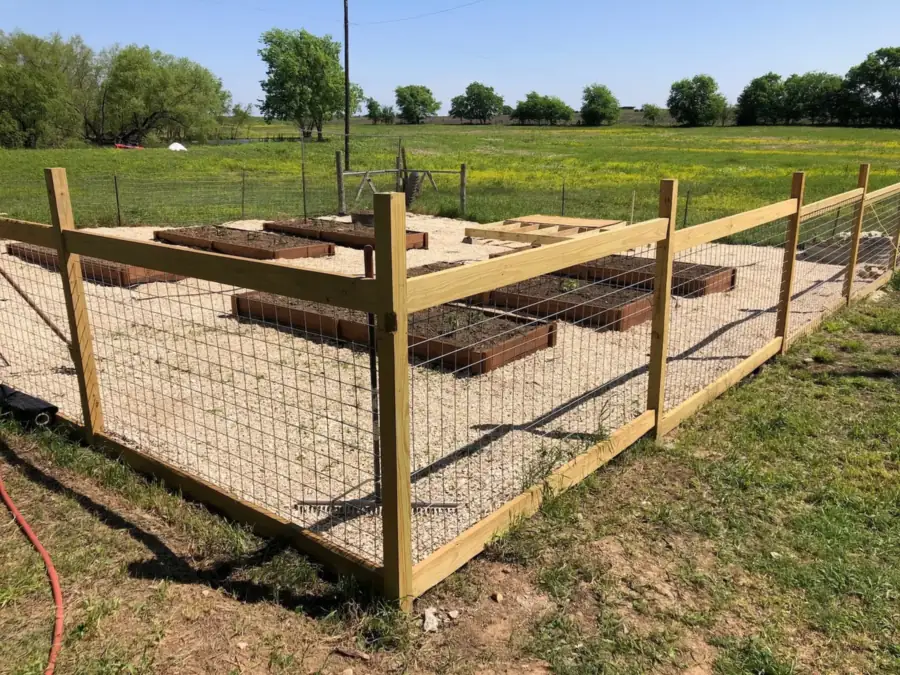 Wood-framed wire mesh garden fence around raised beds on open land, built by Sagamore Fence & Deck for Jarrell, TX properties