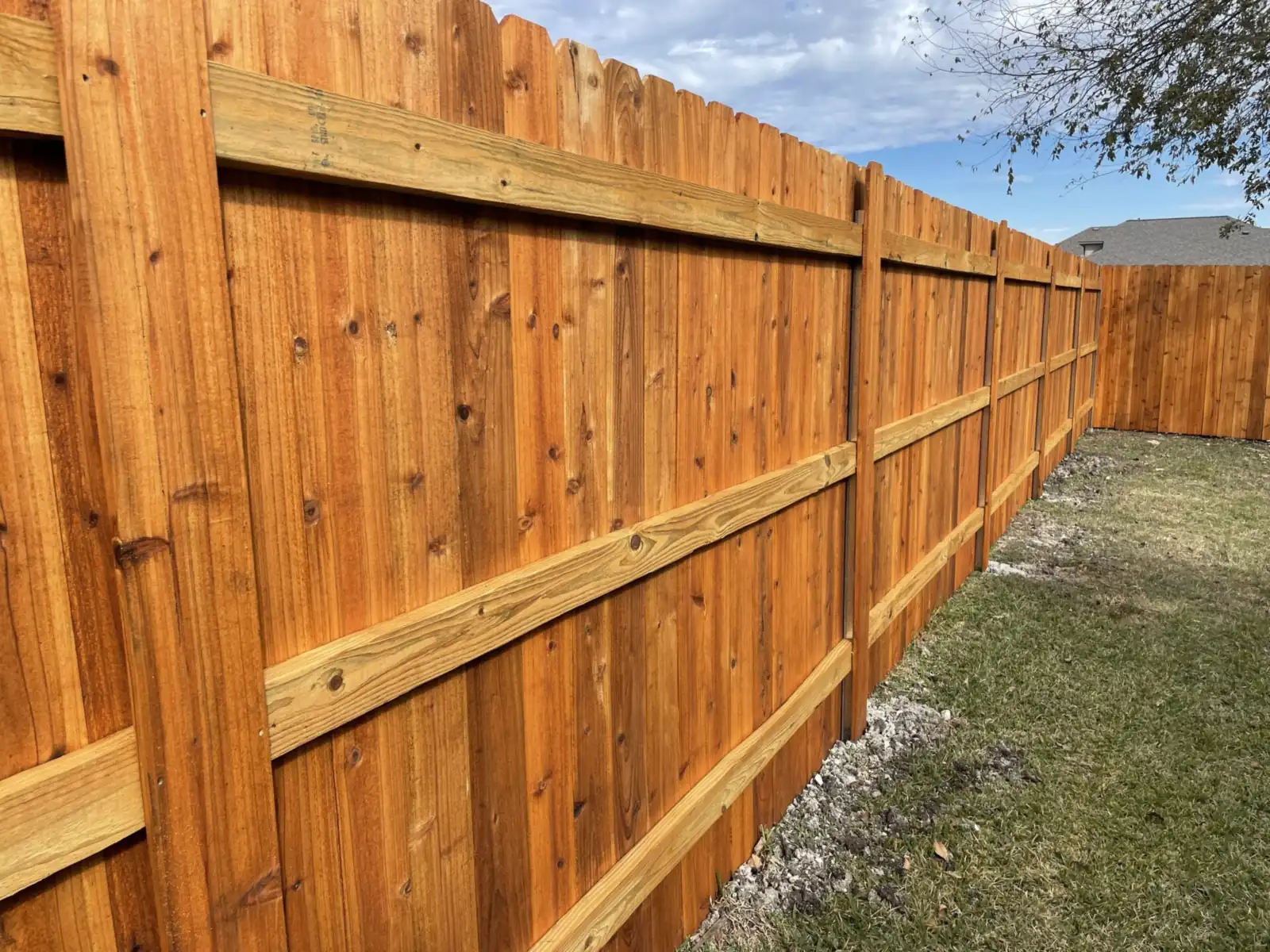 Stained cedar privacy fence with exposed posts and rails along a backyard, built by Sagamore Fence & Deck for Taylor, TX homes