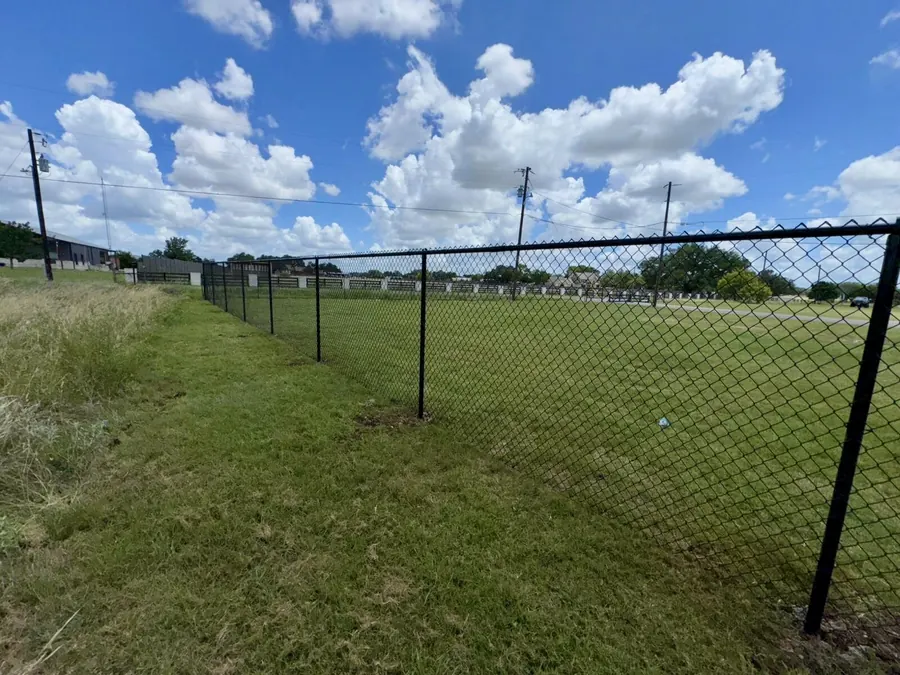 Black chain link fence along an open grassy field, built by Sagamore Fence & Deck for Taylor, TX properties