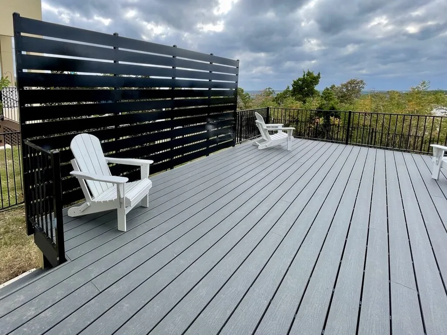 Gray Trex composite deck with a black horizontal privacy screen and white lounge chairs by Sagamore Fence & Deck, deck builder for West Lake Hills, Rollingwood and Austin 78746